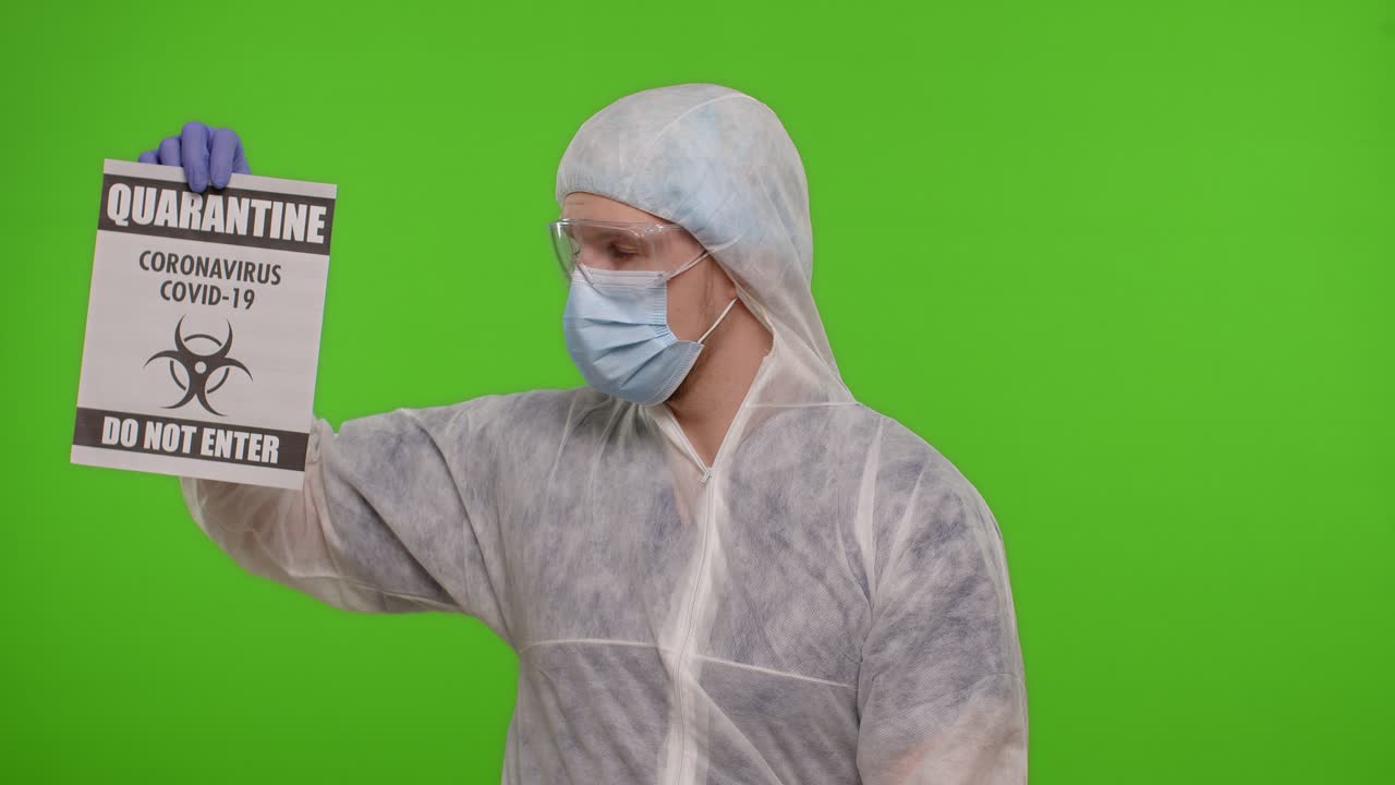 옷을 입은 의사가 종이에 경고 문자 슬로건을 표시합니다. 격리 코로나19 코로나 바이러스는 들어오지 마십시오.
