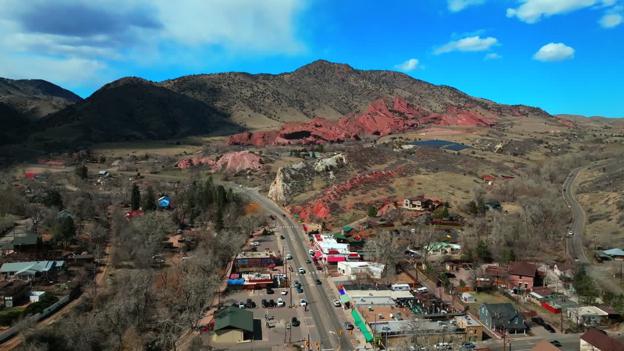 Winter downtown Main Street Morrison Colorado aerial drone Red Rocks Park and Amphitheater Mount Morrison Bear Creek sunny blue sky cloudy neighborhood traffic car driving forward motion