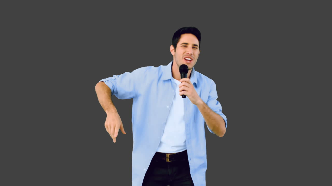 남자가 마이크에 노래하고 회색 배경에서 춤을 춘다