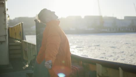 trabajador portuario en uniforme naranja de pie junto a la tabla del barco. destello de la lente. cámara lenta