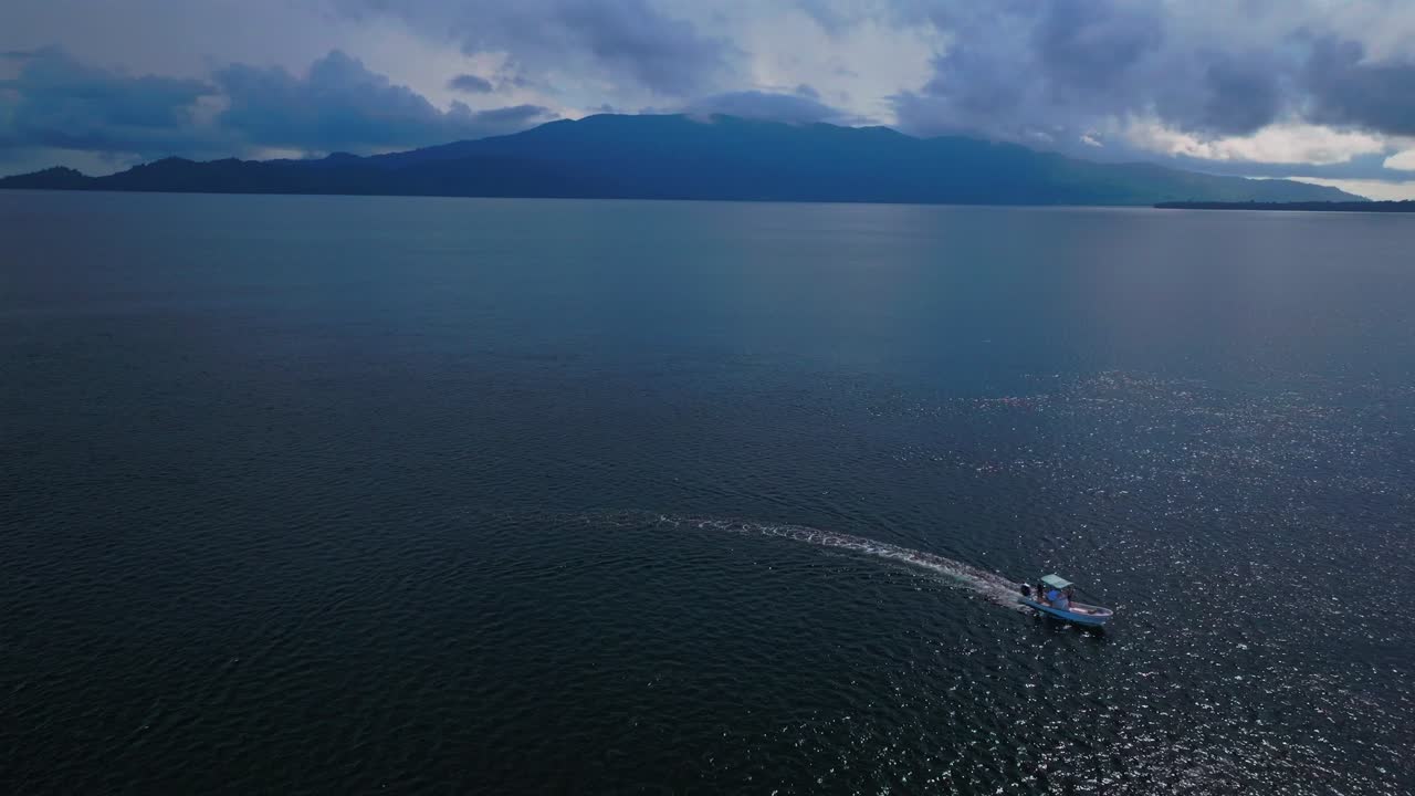 Speed power fishing idling trolling boat Wewak Madang Yuo Island Dogreto Bay Papua New Guinea aerial drone PNG Cape Wom deep Pacific Ocean Bismarck Sea tropical island pristine coastline static shot