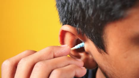 person cleaning their ear with a cotton swab