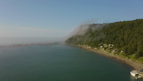 Picturesque-aerial-view-of-a-fishing-village-as-mist-climbs-up-the-rugged-cliffs-along-the-North-Atlantic-coast