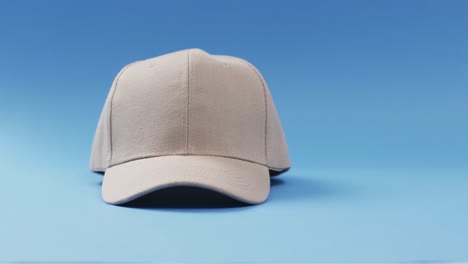 video of beige baseball cap and copy space on blue background