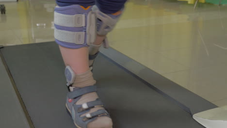 close up view of small boy feet on treadmill in the special orthopedic bandage and foot wear