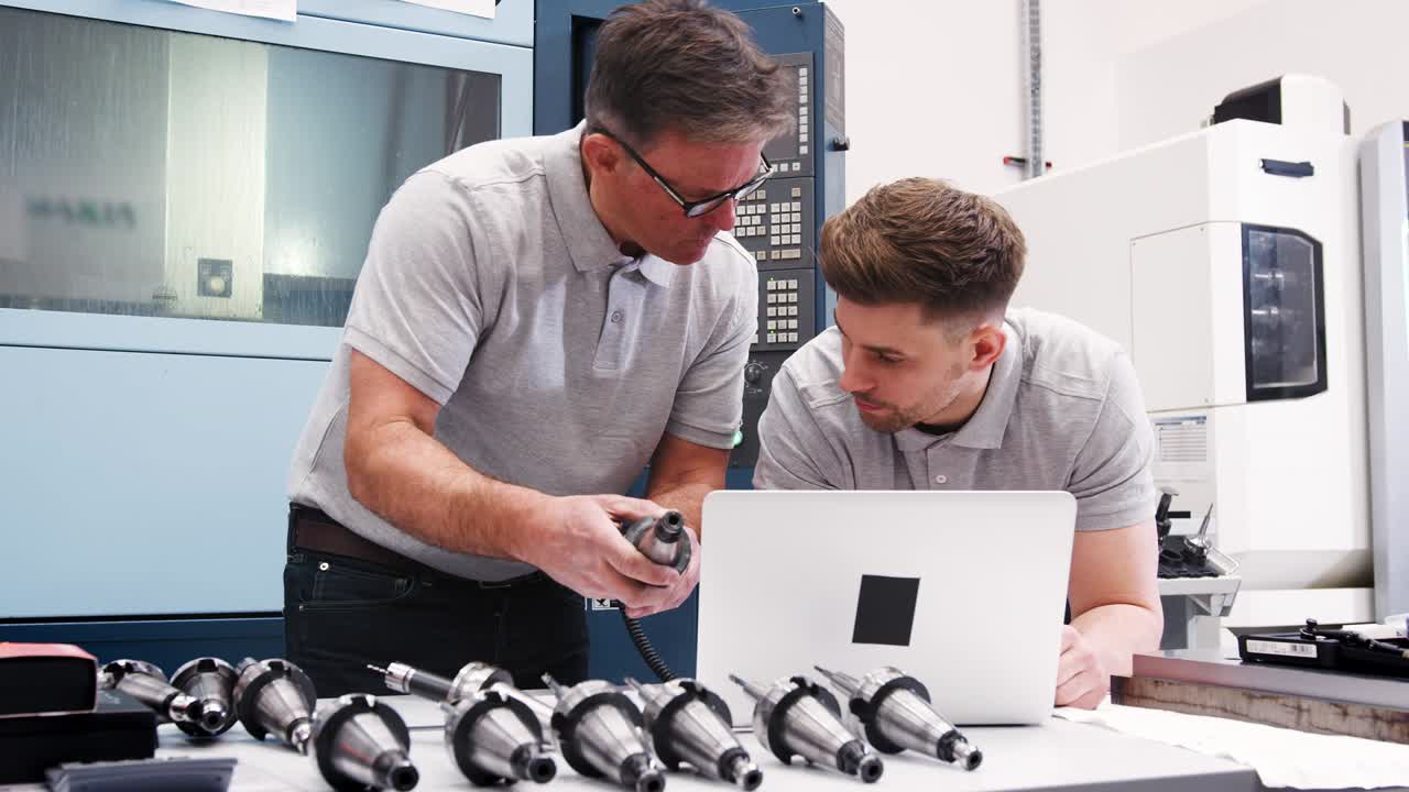 Engineer Showing Apprentice How Use CAD Software On Laptop