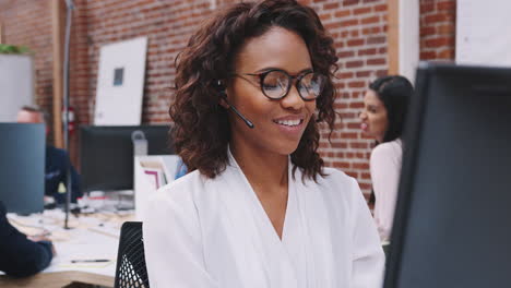 Female-Customer-Services-Agent-Working-At-Desk-In-Call-Center