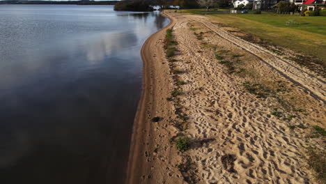 vista aérea a lo largo de una playa tranquila en una comunidad residencial en pistas de vehículos de día soleado