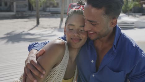 pareja feliz abrazándose sentada en una playa soleada, en cámara lenta