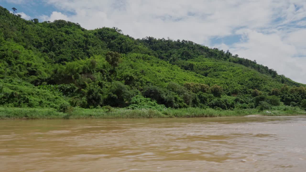 Navigando lungo la giungla su un fiume, il Mekong del Sud-est asiatico, con la foresta pluviale sullo sfondo.
