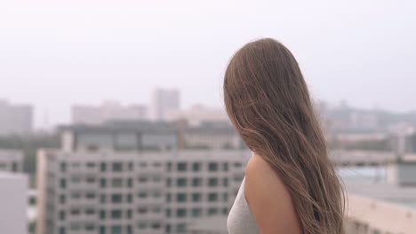 girl with loose hair stands and looks at city slow motion