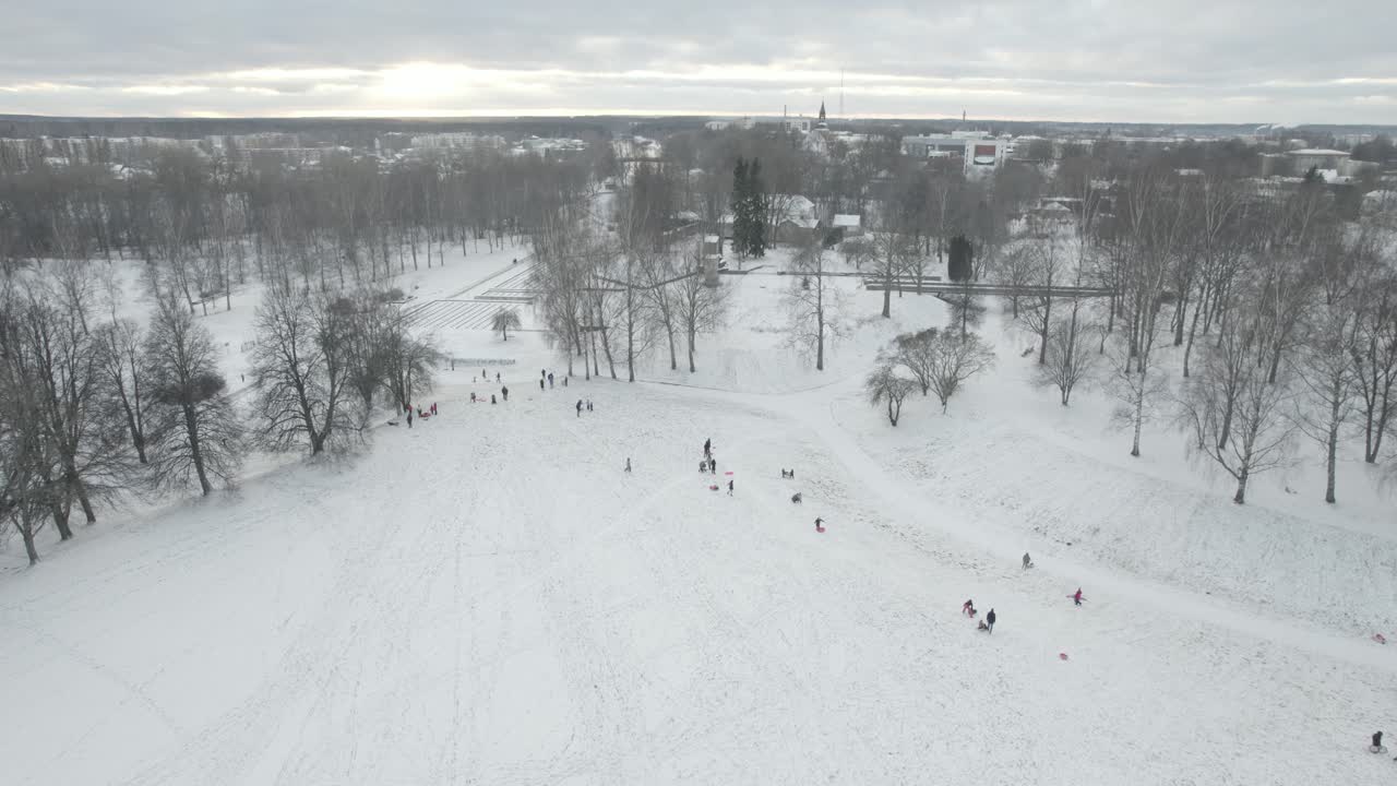 A breathtaking aerial view of Valmiera city, showcasing the winding Gauja River surrounded by snow-covered landscapes and residential areas under a wintry sky.