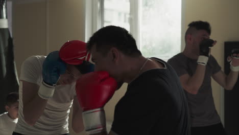 sportsman and trainer friendly sparring in sports gym. professional athletes battle exercising in martial arts club slow motion. boxers training