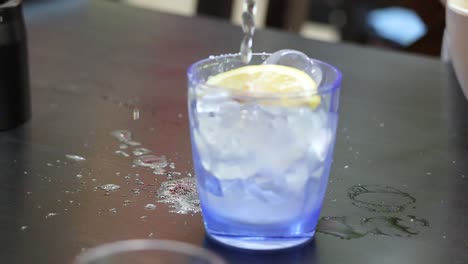 refreshing soda being poured into glass with lemon slice garnish