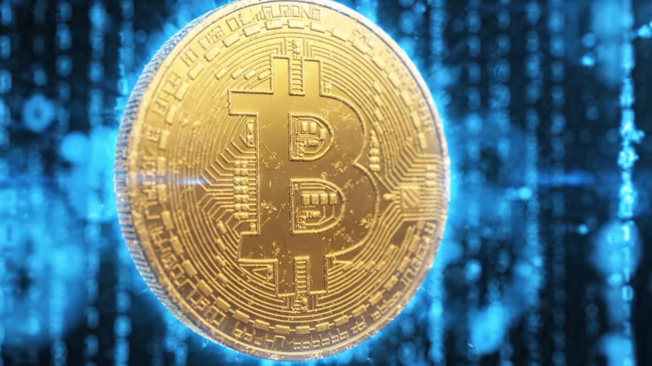 Una moneta Bitcoin scintillante circondata da display di codice binario, che simboleggia l'ascesa delle criptovalute nell'era digitale e il suo impatto sulle transazioni finanziarie