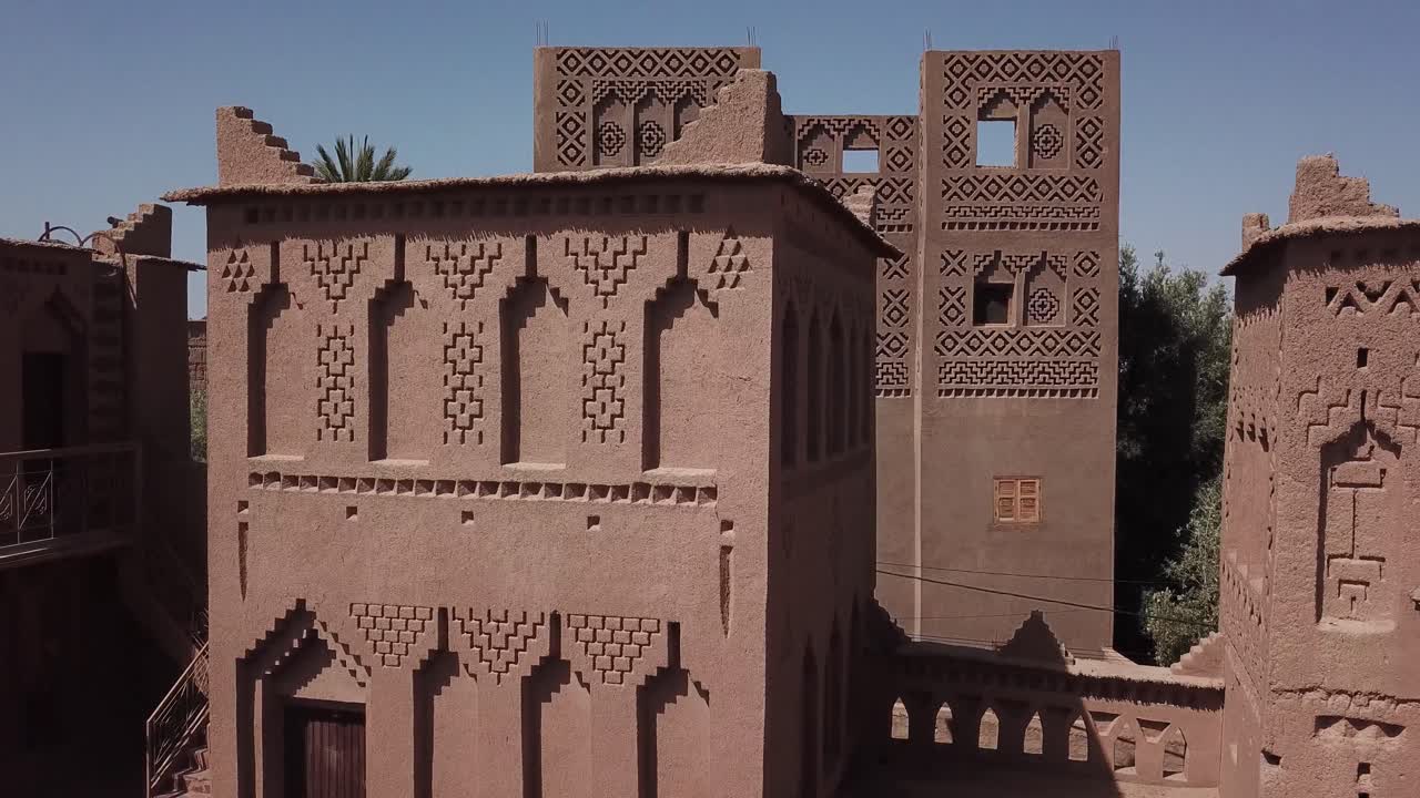 Halvbild som visar detaljerad geometrisk lerornamentering på en traditionell Kasbah-vägg. Berberdesignen och krenelerad arkitektur framhäver marockanskt hantverk i Ouarzazate