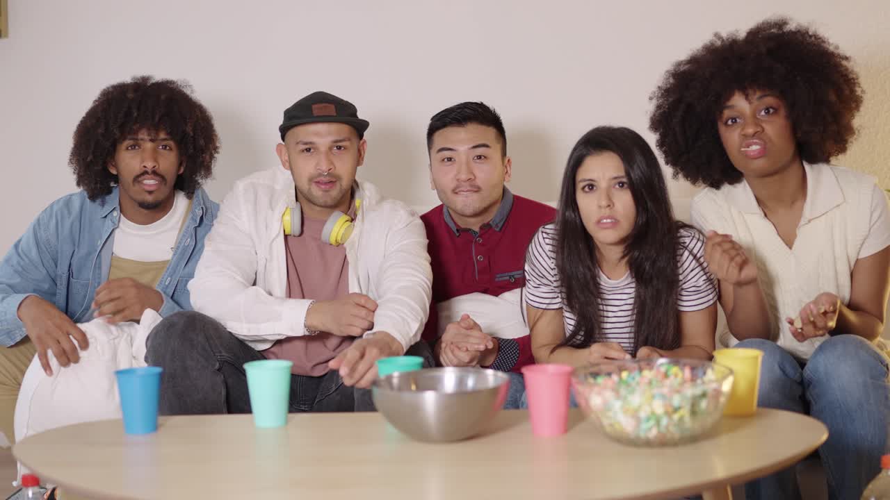 Group of friends watching TV and eating popcorn