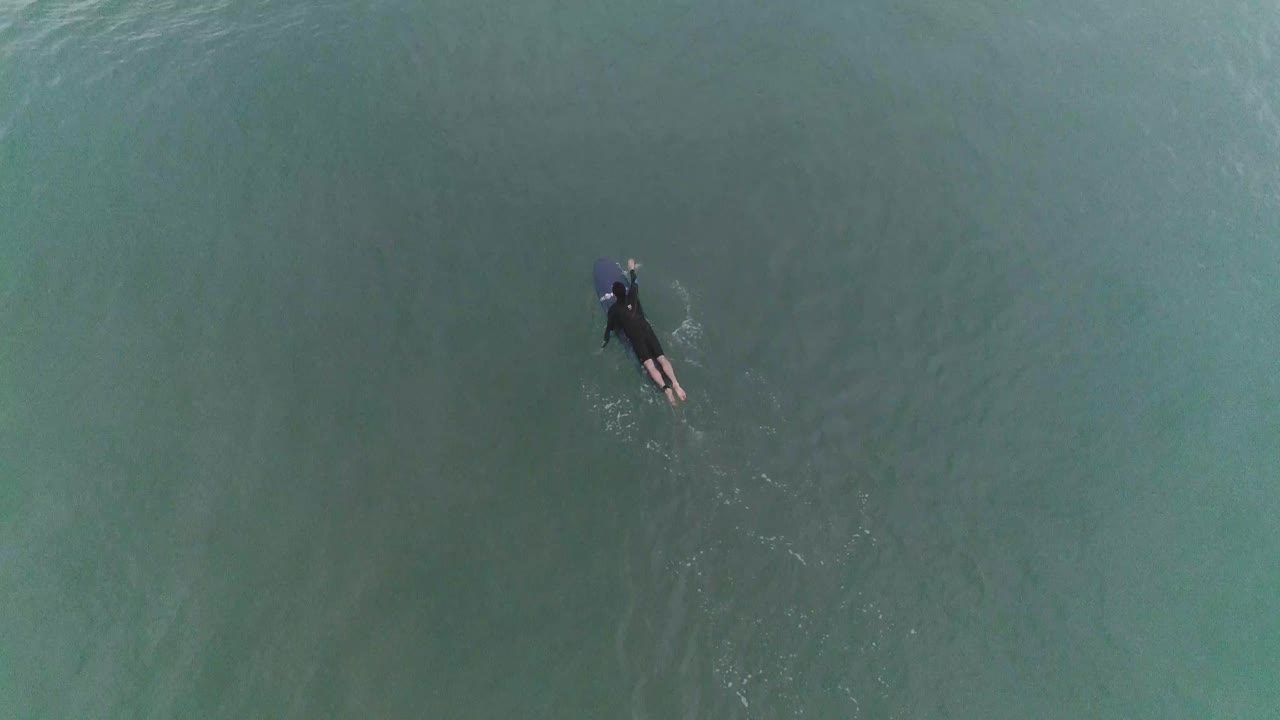 View from top of surfer paddling in slow motion.