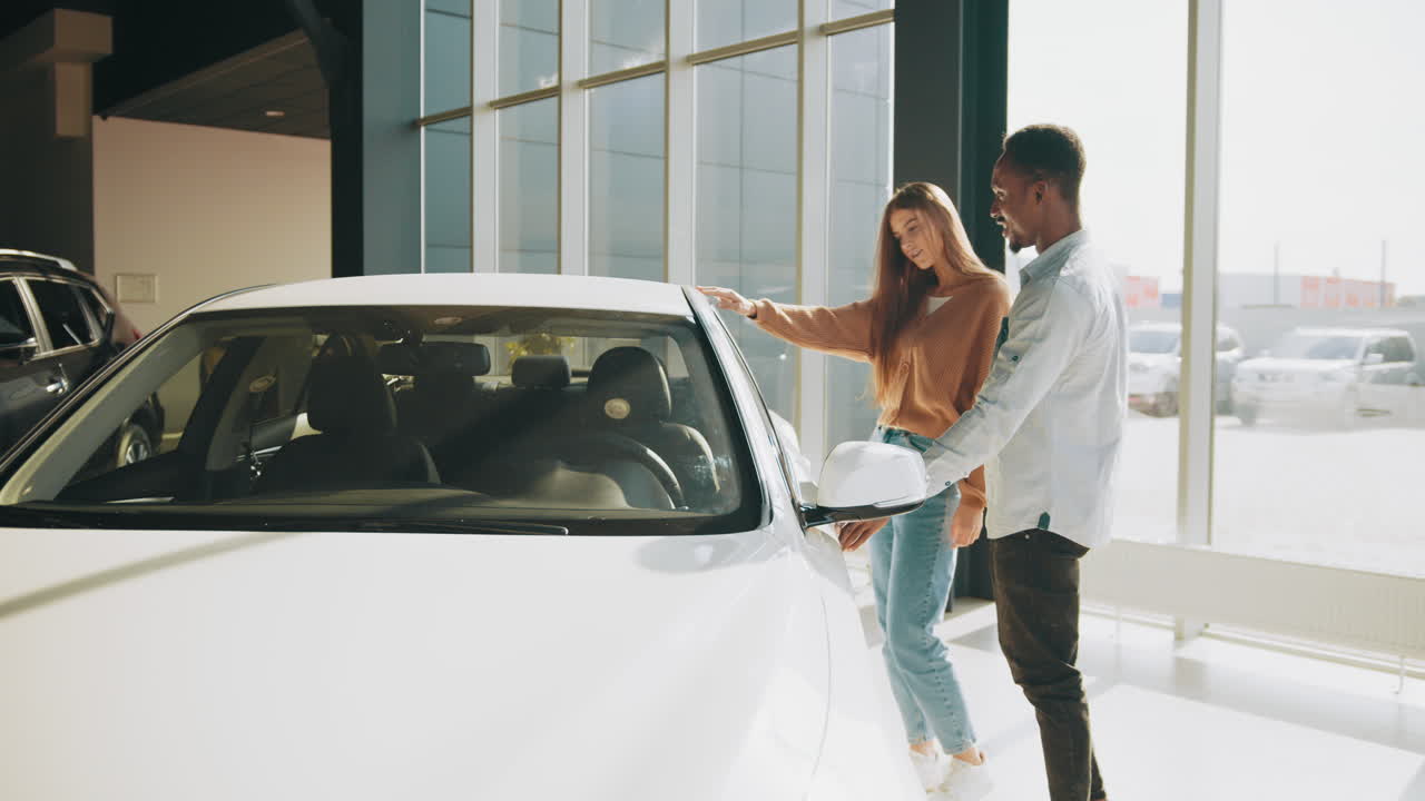 una pareja mirando un coche en una sala de exposiciones