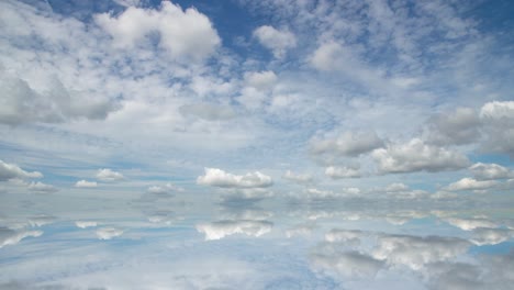 futuristic background consisting of time lapse clip of white fluffy clouds over blue sky and their reflection, video loop