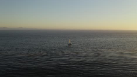 Velero-Solo-En-El-Océano-Durante-La-Hermosa-Y-Pintoresca-Puesta-De-Sol,-Vista-Aérea-De-Pájaros