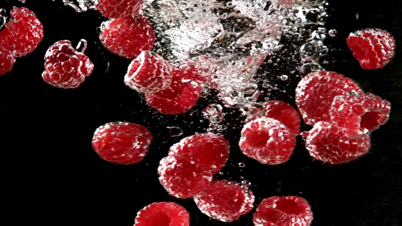 Fresh Red Raspberries Falling into Water with Bubbles