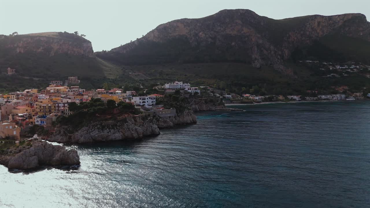 Aerial 4K footage of Porticello coastal village in Sicily Italy showing colorful houses on rocky cliffs turquoise sea Monte Catalfano and the coastline stretching toward Aspra and Bagheria