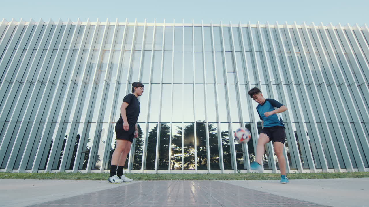 Two Female Football Players Juggling a Ball Outdoors