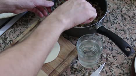 toma estática de manos rellenando una empanada.
