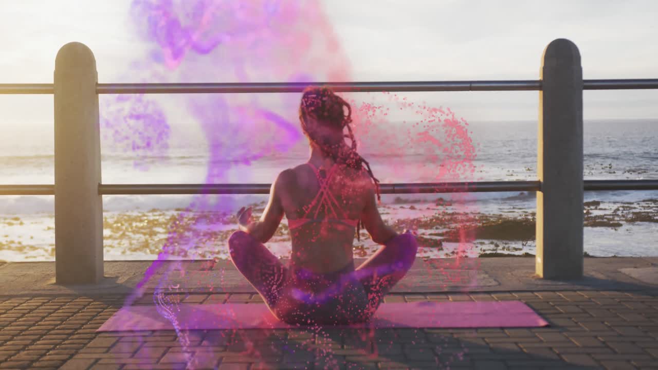 animación de manchas coloridas sobre una mujer biracial meditando junto al mar