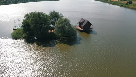 small island and a house in the middle of the river. aerial view of beautiful green island surrounded by water. camera moves round.