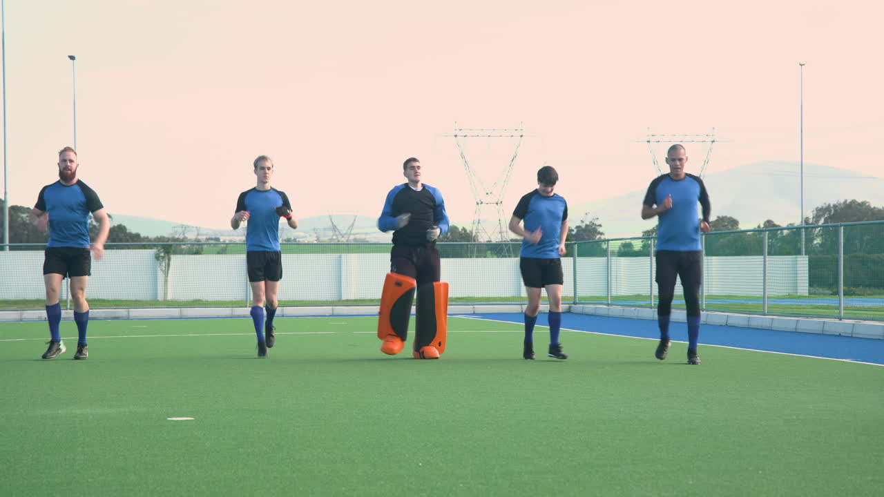 Male hockey players jogging on field, preparing for practice session