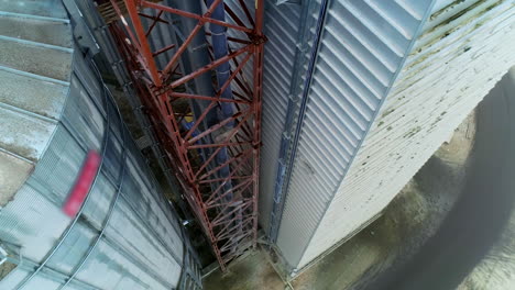 metal brown tower with tube inside attached to a silo tank and warehouse. descending footage along the granary premises. top view.