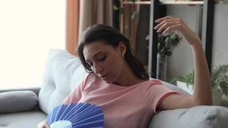 tormented by hot weather indian woman using fan cooling herself