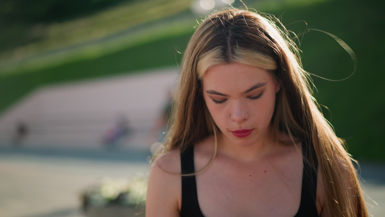 램프 기둥과 초록색을 특징으로하는 흐릿한 배경으로 아래로 초점을 맞추는 동안 상하는 여자가 멀리서 지나갑니다.