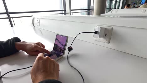 individuals using smartphones at a public charging station