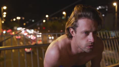 caucasian shirtless male doing sport on a bridge in the evening