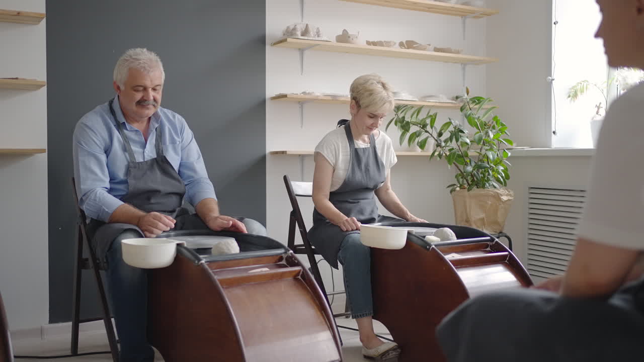 A young woman teaches a group of senior women and a man of 60-70 years old to pottery. Activities for the elderly