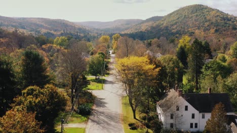 aerial drone shot over a road with rows of ouses on both sides in litchfield county, connecticut, united states with the view of hilly terrain in the background