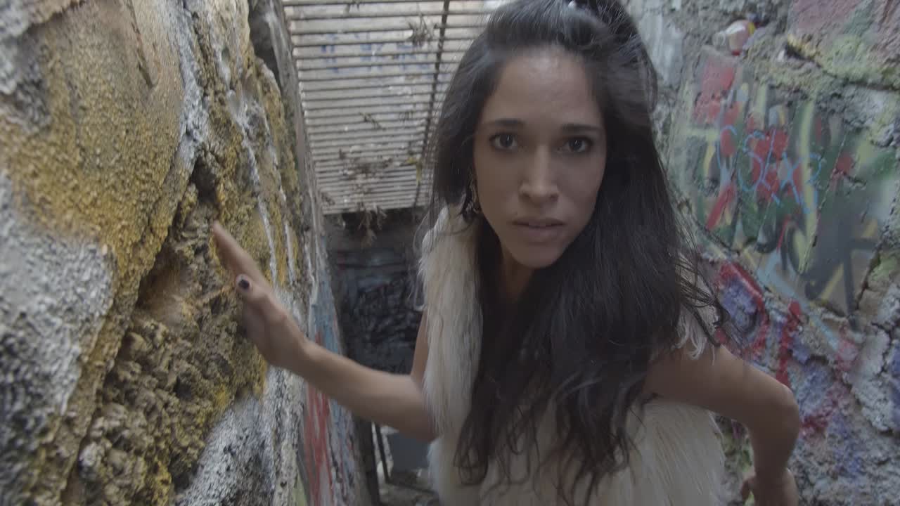 High angle of a woman with long dark hair intensely staring into the camera lens and walking up the steps