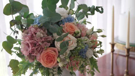 elegant pastel flower bouquet of roses and hydrangeas with eucalyptus by wedding candles