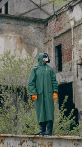 survivor in protective chemical suit. person in infected zone standing alone on the background of empty ruined building. air pollution. vertical video