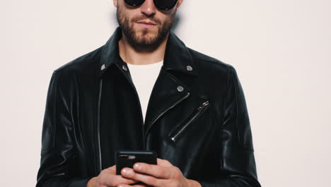 man in a leather jacket and sunglasses using a phone