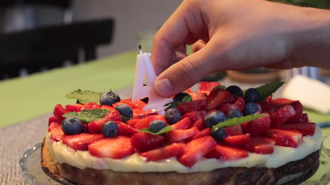 남자 손을 닫습니다 케이크에서 번호 4 모양 생일 촛불을 걸립니다