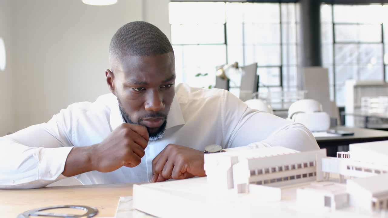 Architect examining building model in office, focusing on design details