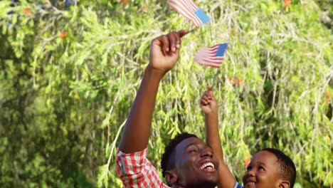 Eine-Familie,-Die-Sich-Umarmt,-Während-Sie-Eine-Amerikanische-Flagge-Hält