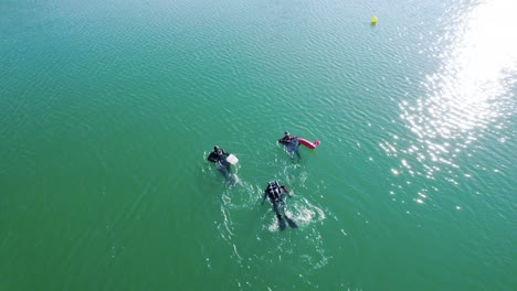 aerial view of 3 divers in a lake in southern france, swimming towards shore