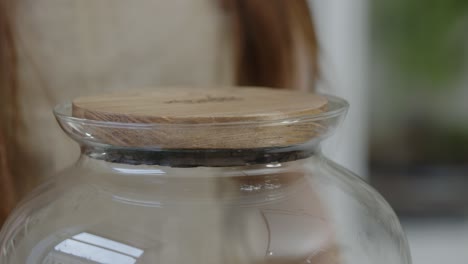 a young female botanist creates a tiny live forest ecosystem in a huge glass jar - closing the terrarium - a tight close-up