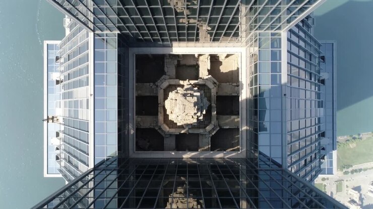 Drone capturando imagens, pairando sobre torre de rio, revelando átrio central e vidro, exibindo simetria