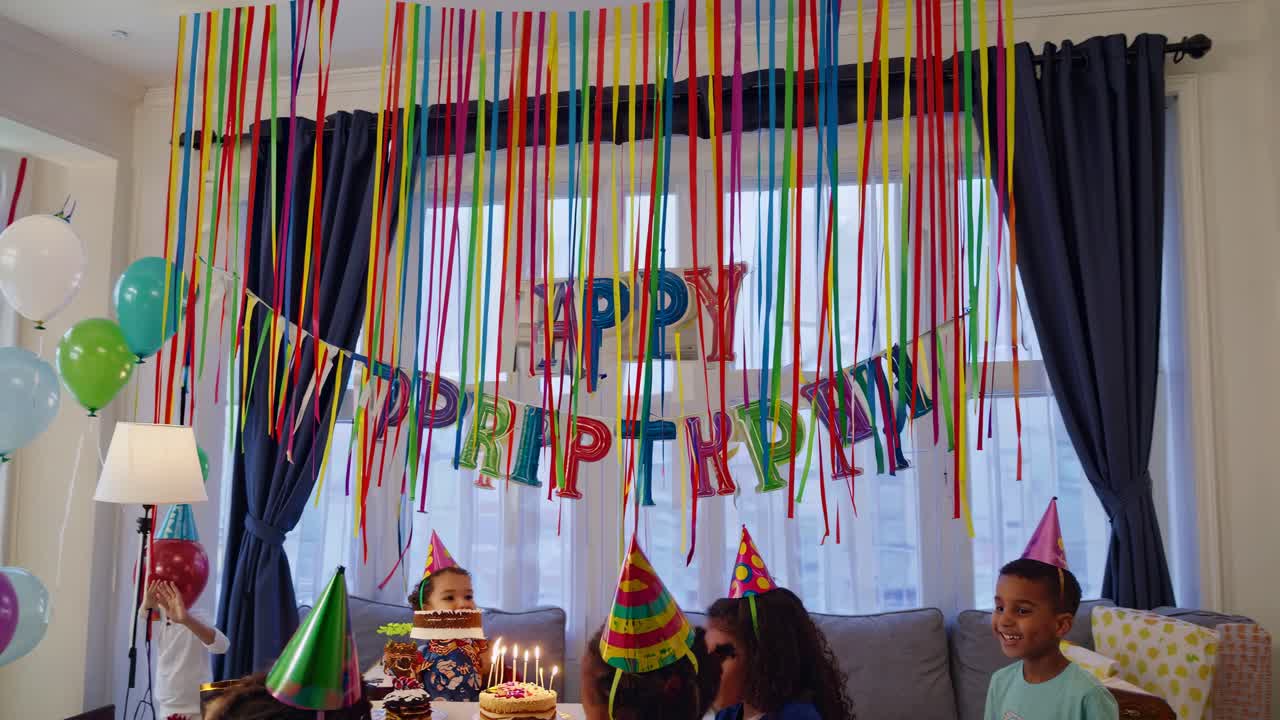 A lively birthday party video scene from a low angle, capturing kids in party hats, colorful